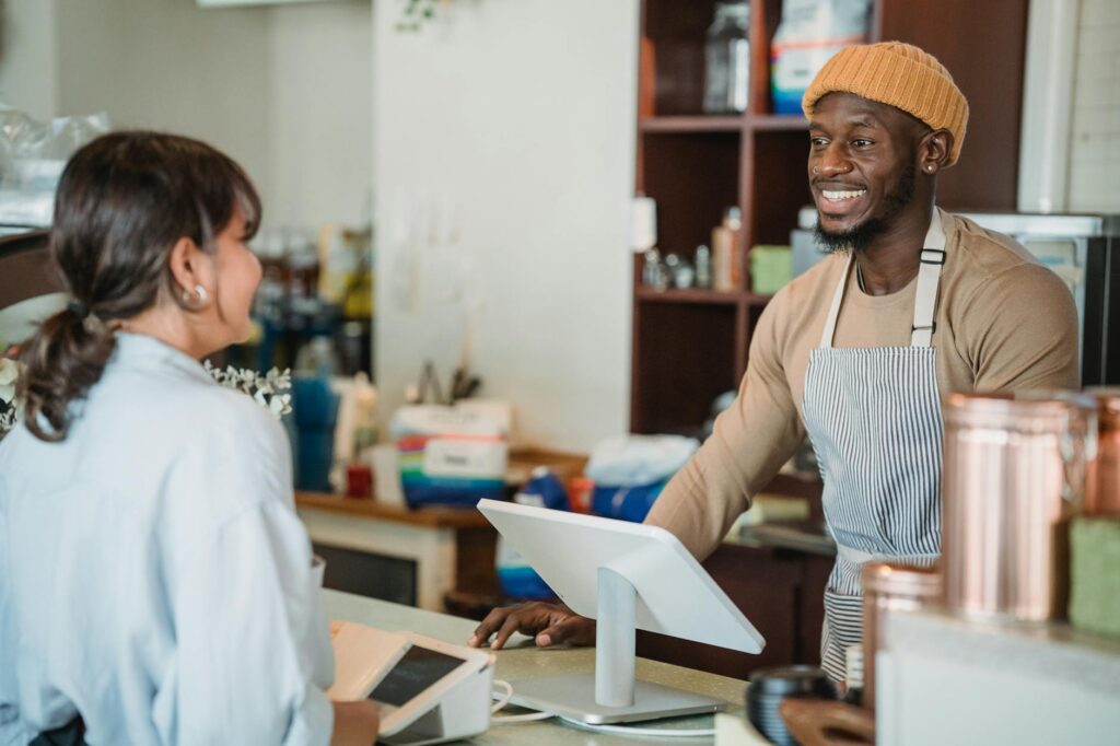 A cheerful barista engaging with a customer at a café counter, creating a welcoming atmosphere.